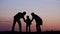 Family silhouettes put hands together, perfect team and support, sunset deal