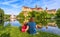 Family sit near medieval Sigmaringen Castle, Germany. Young woman and her child are at river shore in summer