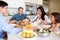 Family Sitting Around Table Saying Prayer Before Eating Meal