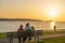 Family sitting on the bench, enjoy the sunset time at English Bay Beach