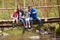 Family Sitting On Bridge Fishing In Pond With Net