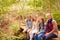 Family sitting on a bridge in a forest, looking to camera