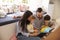 Family Sitting On Floor Reading Story At Home Together