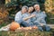 Family sitting in a garden with apples and pumpkin