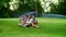 Family sitting on green in meadow. Parents and kids using digital tablet in park