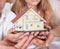 Family Sitting Holding Miniature Model Of House