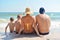 Family sitting on the sand on the beach. Family holidays by the sea. Happy children and parents on vacation in the tropics.