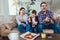 Family sitting on a sofa and playing video games and eating pizza