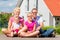 Family sitting on street in front of suburban house