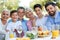 Family sitting at table outdoors, smiling