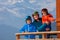 Family in ski helmets on balcony, smiling over Alpine panorama