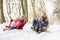 Family Sledging Through Snowy Woodland