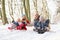 Family Sledging Through Snowy Woodland