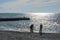 A family with a small child on the shore of the winter sea among seagulls at sunset