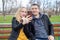 The family speaks on video call. Husband and wife are sitting on a swing in the park and have fun talking on a smartphone with