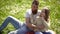 Family spend leisure outdoors. Dad and daughter sits on grass at grassplot, green background. Child and father posing