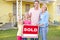 Family Standing By Sold Sign Outside Home