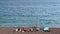 Family is sunbathing on the seashore, a surfboard is lying nearby