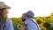 Family in sunflower field, young siblings in straw hats together on a walk at summer outdoors