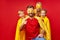 Family of superheroes in costumes posing in studio with red background
