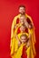 Family of superheroes in costumes posing in studio with red background