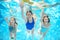 Family swims in pool under water, happy active mother and children have fun underwater, kids sport