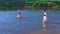 Family in swimsuits in river swimming and bathing in water at Summer warm day.