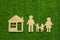 Family symbols and houses made of natural wood on the background of green grass symbolize the eco-house.