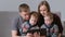 Family with tablet. Mom, dad and two sons twins looking at tablet sitting in sofa.