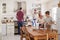 Family With Teenage Children Laying Table For Meal In Kitchen