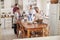 Family With Teenage Children Laying Table For Meal In Kitchen