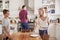 Family With Teenage Children Laying Table For Meal In Kitchen