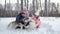 Family of Three Have Fun with Sledge Dogs on Snow