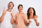 Family of three, mother, father and son standing over white isolated background amazed and surprised looking up and pointing with