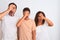 Family of three, mother, father and son standing over white isolated background peeking in shock covering face and eyes with hand,