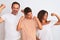 Family of three, mother, father and son standing over white isolated background showing arms muscles smiling proud