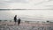 Family of three people walking on a beach. Mother, daughter and son going to water, holding hands.