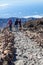 Family from three people wearing wind proof jackets with hood walking on alpine hiking route in the Teide volcano, Canary Islands