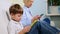 A family of three sit on the couch and uses digital devices. The boy using tablet and mother browsing information on the