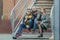 Family of three street urban portrait sitting on metal stairs at brick building background