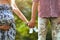 Family together holding baby shoes in hands and standing the summer park. Woman is pregnant.