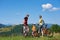 Family tourists bikers, mom, dad and child resting with bicycles on grassy hill