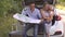 Family of travelers with child in sunglasses study the map sitting in the trunk