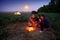 Family traveling and camping, twilight, cooking on the fire. Beautiful nature - field, forest, stars and moon