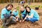 Family with two children planting a tree in the forest