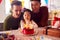 Family With Two Dads And Daughter Celebrating Parents 30th Birthday At Home With Cake And Candles