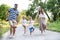 A family with two small sons hopscotching barefoot on a road in park on a summer day.