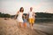 Family vacation in summer. Young Caucasian family foot walking barefoot sandy beach, shore river water. Dad mom holding hands two