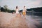 Family vacation in summer. Young Caucasian family foot walking barefoot sandy beach, shore river water. Dad mom holding hands two