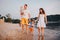 Family vacation in summer. Young Caucasian family foot walking barefoot sandy beach, shore river water. Dad mom holding hands two